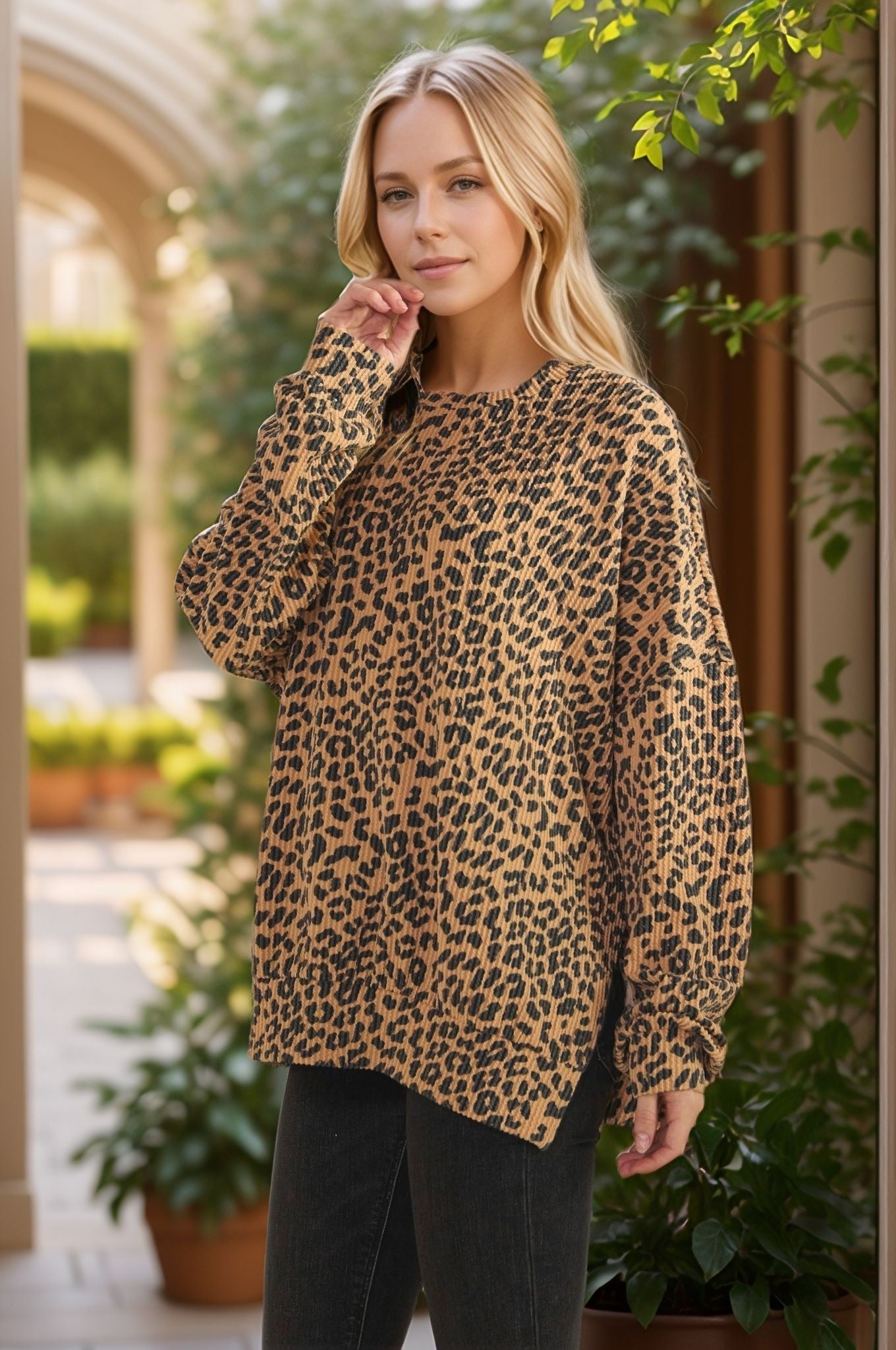 Woman wearing a ribbed long sleeve leopard print top with a relaxed fit, paired with black jeans in an outdoor setting.