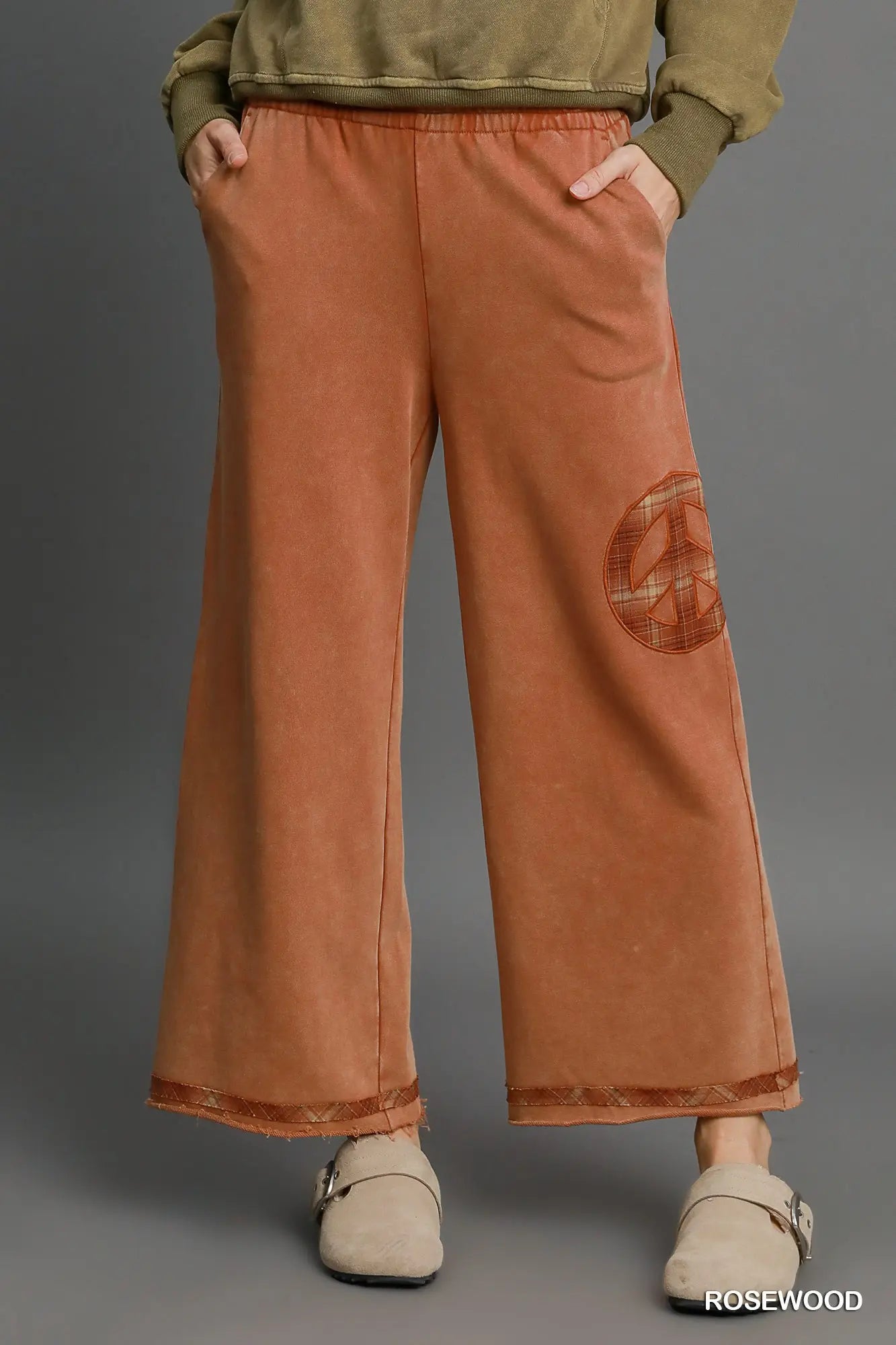 Rosewood wide-leg pants with plaid peace-sign patch and raw hem detail, styled with beige clogs