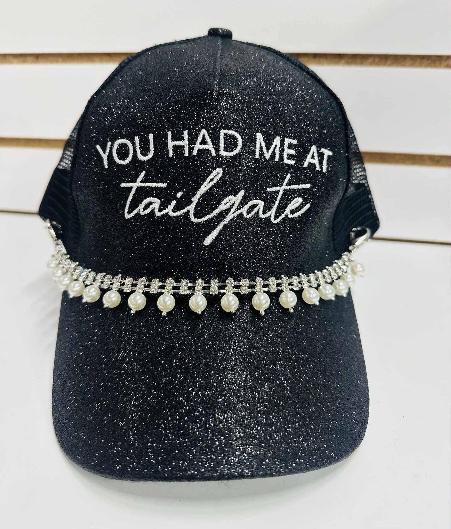 Black glitter trucker hat with “You Had Me at Tailgate” embroidery, pearl rhinestone trim, and mesh back with pearl accents.