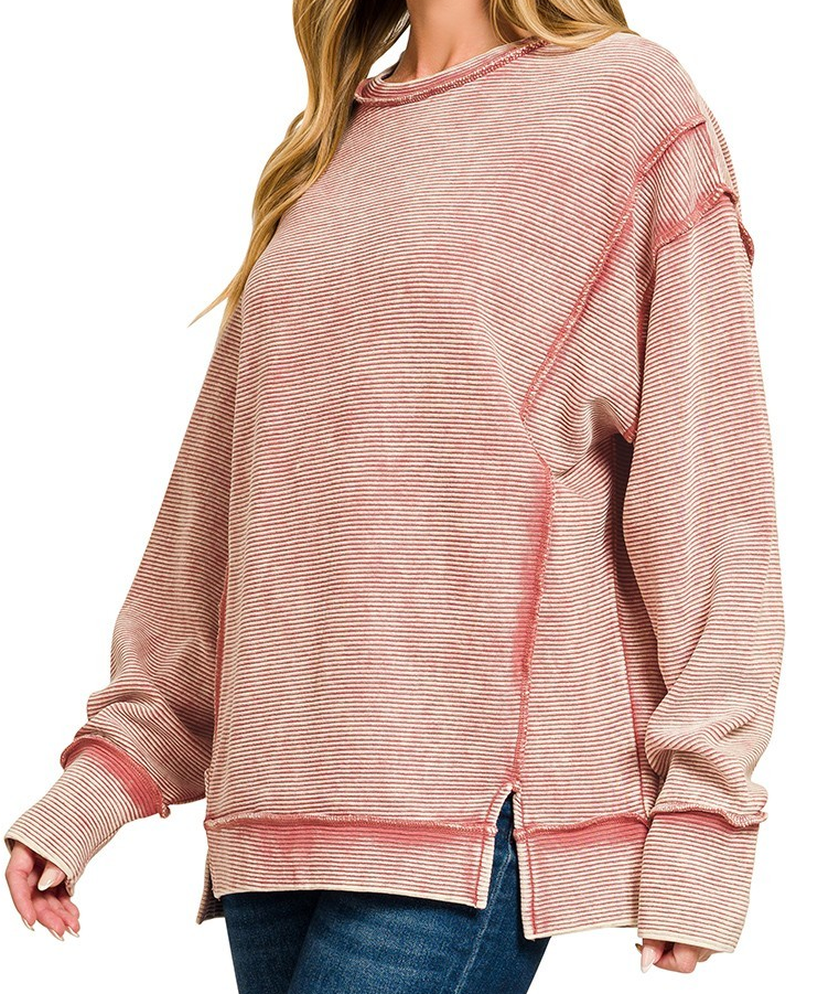 Model wearing acid washed ribbed exposed seam pullover in winter rose with long sleeves and side slits.