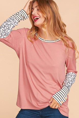 Woman wearing a rose pink ribbed top with long sleeves featuring leopard and black-and-white stripe contrast prints.