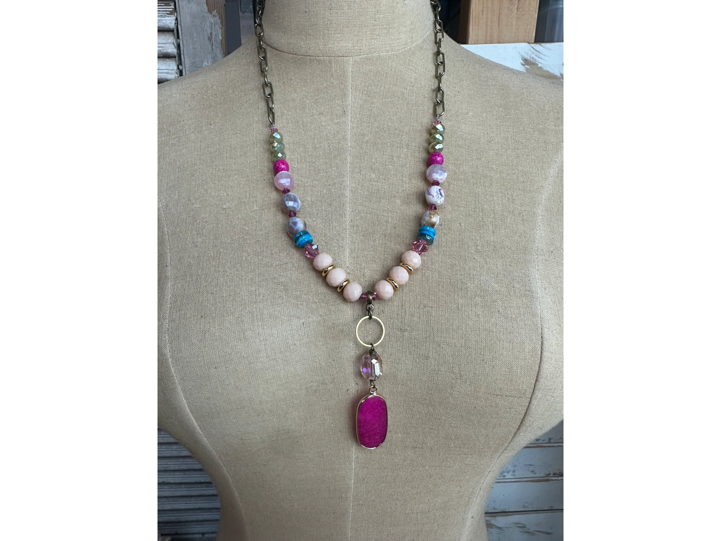 Colorful beaded necklace with pink gemstone pendant on mannequin display