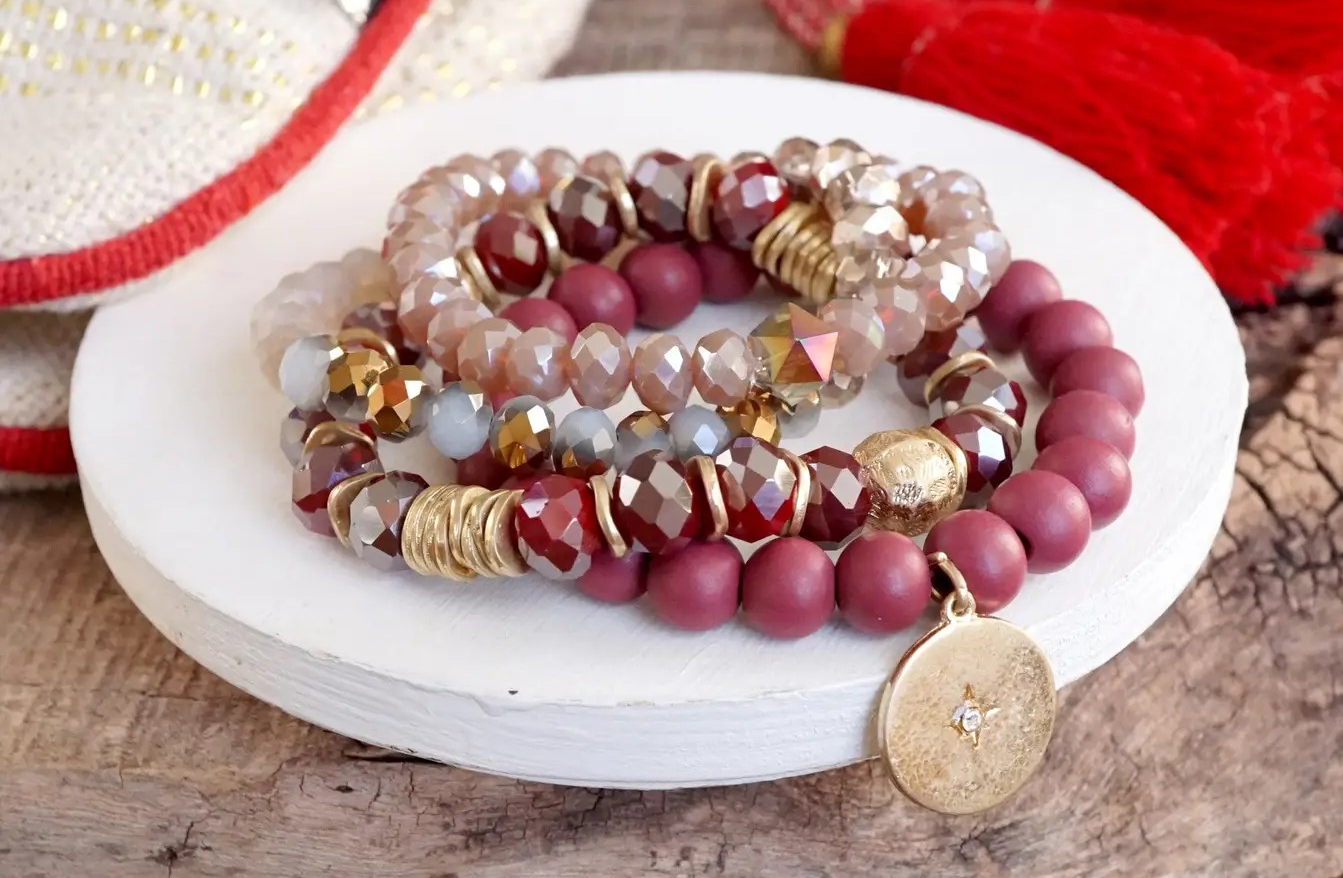 Four-piece beaded bracelet set featuring burgundy matte beads, faceted glass, gold accents, and a gold coin charm with star detail.