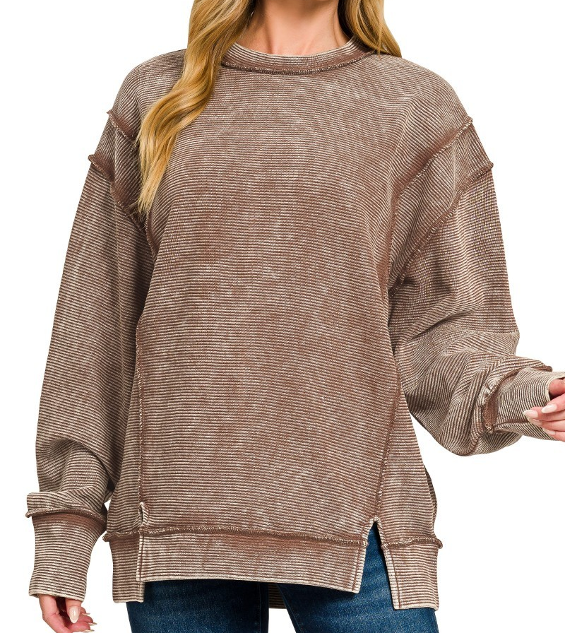 Model wearing acid washed ribbed exposed seam pullover in brown with long sleeves and side slits.