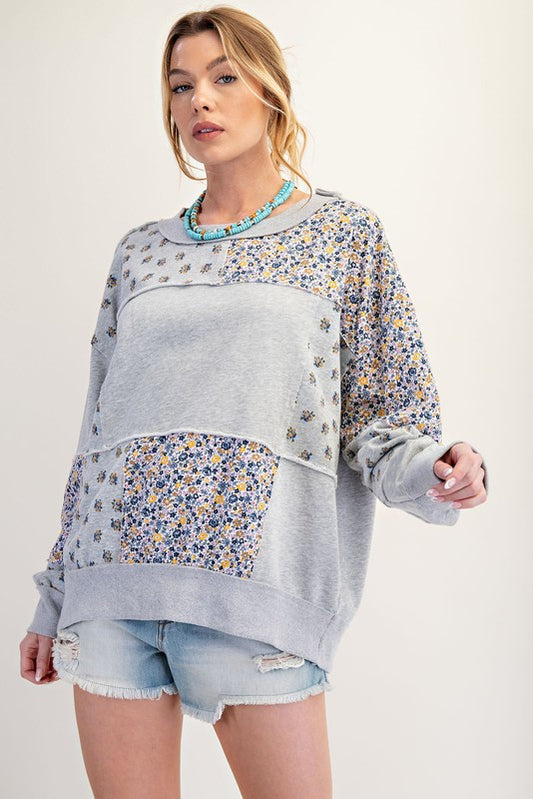 Mineral-washed gray sweatshirt with mixed floral patchwork panels, featuring a relaxed fit. Available in sizes Small, Medium, and Large.