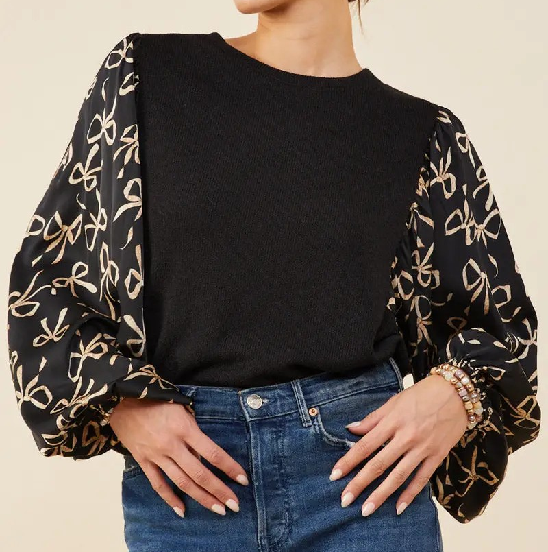 Black top with contrast silky sleeves featuring beige bow print design.