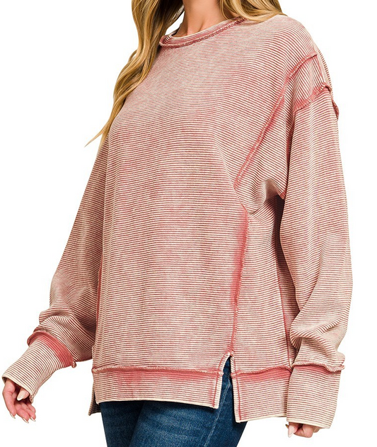 Model wearing acid washed ribbed exposed seam pullover in winter rose with long sleeves and side slits.