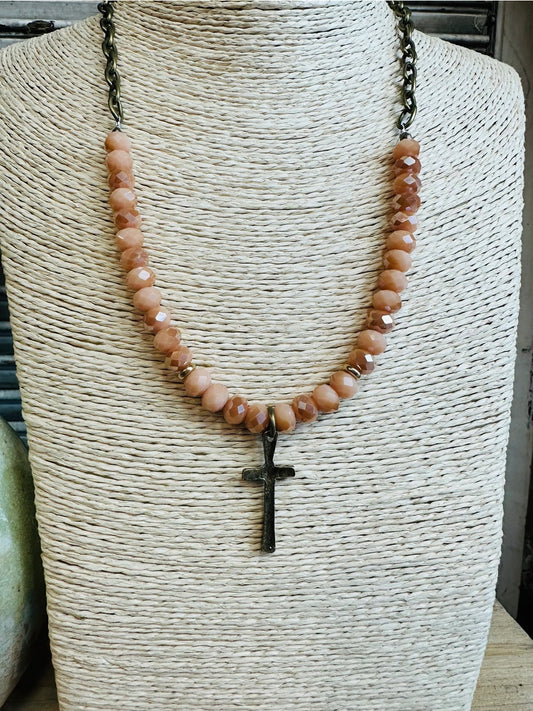 Peach crystal bead necklace with hammered cross pendant on woven display bust

