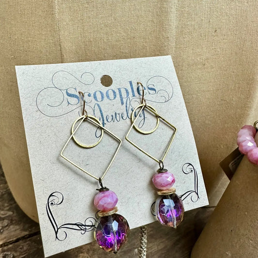 Geometric gold earrings with pink and purple crystal beads on branded card

