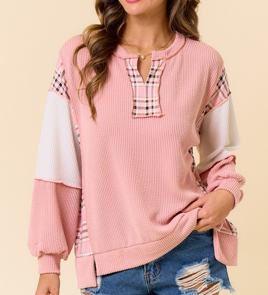 Pink ribbed pullover with plaid accent neckline, shoulders, and side panels, featuring long sleeves and a relaxed fit styled with distressed denim.