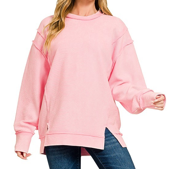 Ribbed exposed seam cotton pullover with relaxed fit, side slits, and long sleeves styled with jeans.