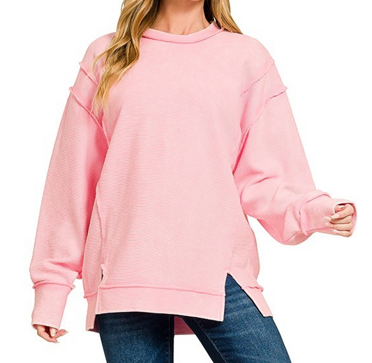 Ribbed exposed seam cotton pullover with relaxed fit, side slits, and long sleeves styled with jeans.