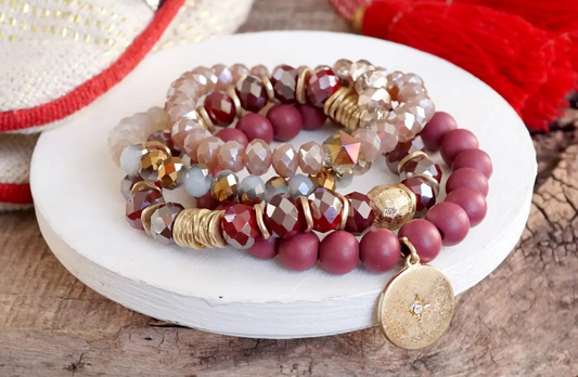 Four-piece beaded bracelet set featuring burgundy matte beads, faceted glass, gold accents, and a gold coin charm with star detail.