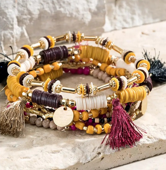 Multi-layer stretch bracelet set with mixed beads, gold accents, and colorful tassels in warm tones