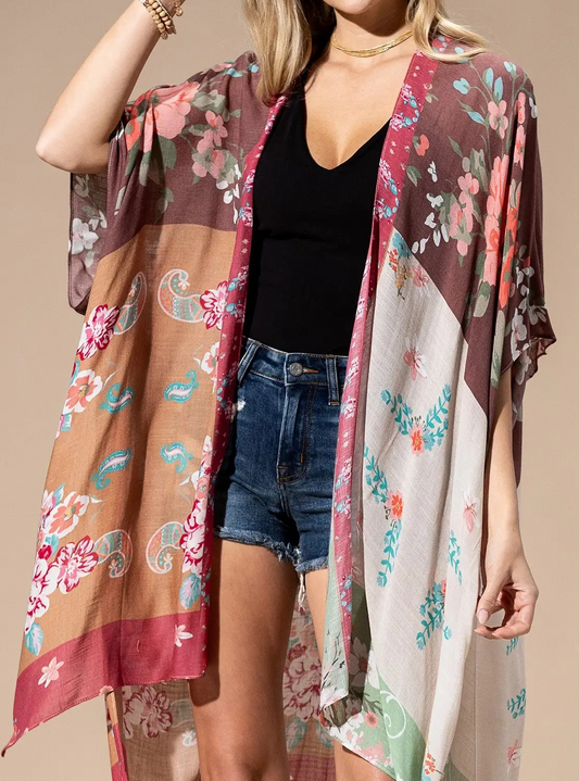 Model wearing a lightweight floral patchwork kimono in earthy colors over a black tank and denim shorts.