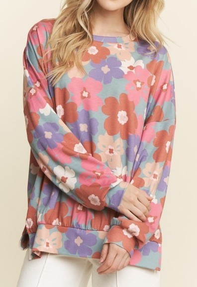 Woman wearing a colorful floral long sleeve top with ribbed hem and cuffs.