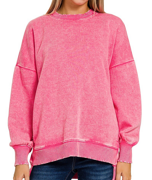 Pink acid washed fleece pullover with long sleeves, ribbed cuffs, and a hi-low hem styled with jeans.