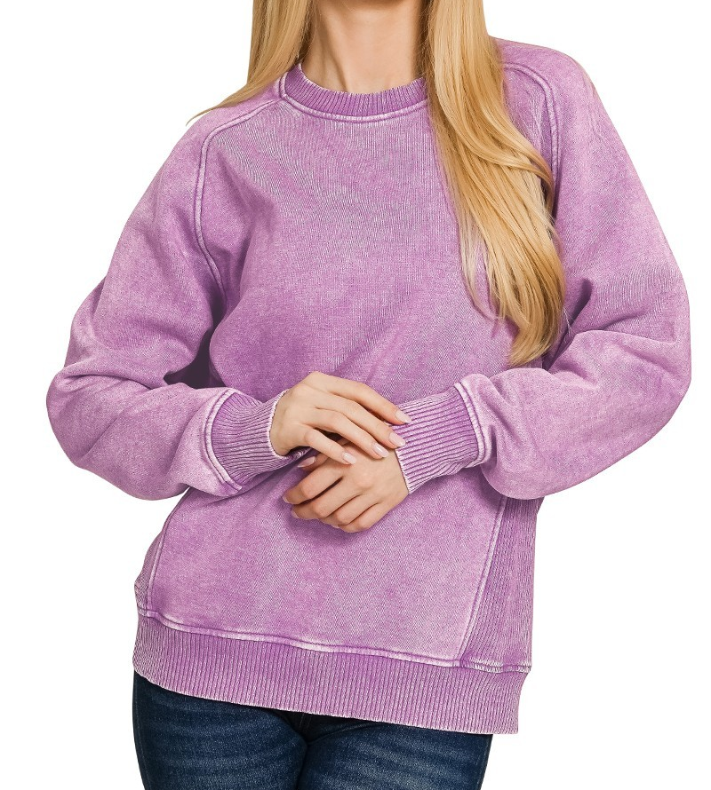 Lavender acid washed fleece pullover with long sleeves, ribbed side panels, and relaxed fit styled with jeans.
