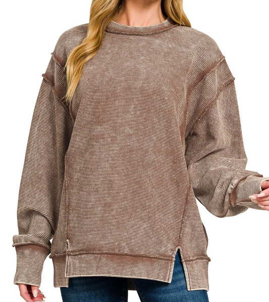 Model wearing acid washed ribbed exposed seam pullover in brown with long sleeves and side slits.